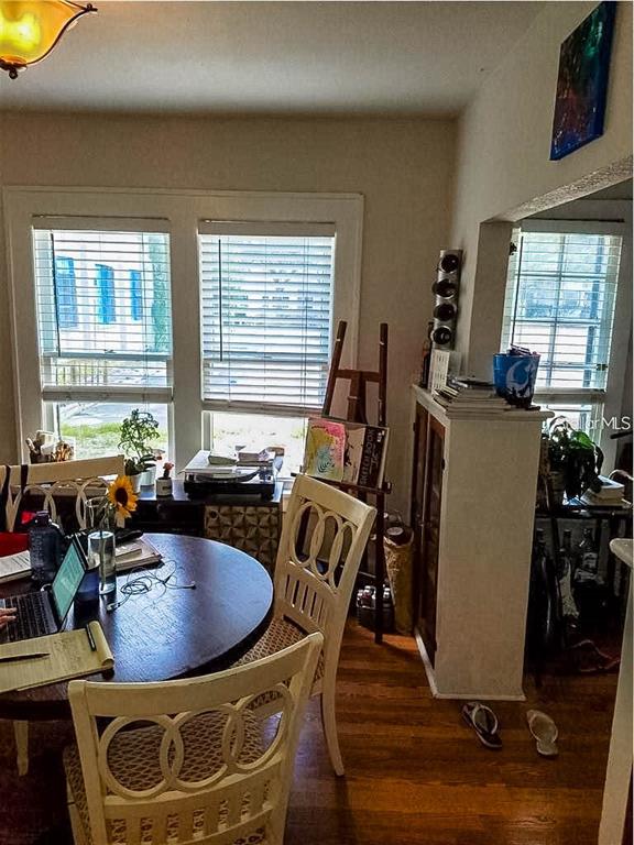 A dining area features a round wooden table, white chairs, and windows with blinds — 1210 HIGHLAND STREET S, ST PETERSBURG, FL