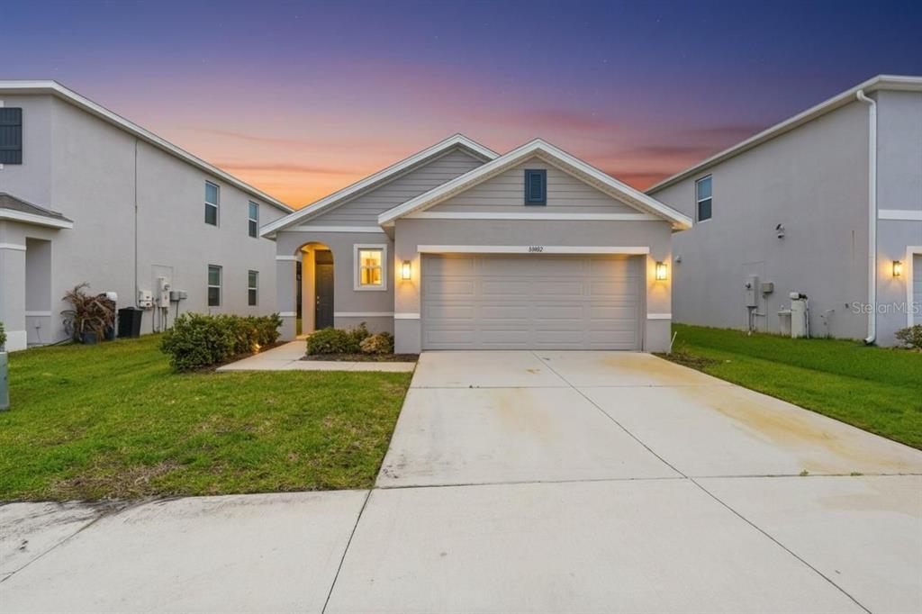 A single-story house with a gray exterior, a two-car garage, and a concrete driveway — 33922 JASPER STONE DRIVE, WESLEY CHAPEL, FL