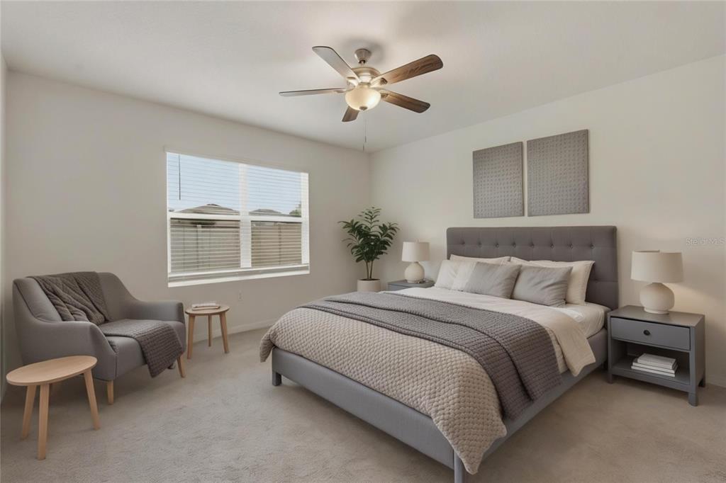 A bedroom features a gray upholstered bed, a matching armchair, and a ceiling fan — 33922 JASPER STONE DRIVE, WESLEY CHAPEL, FL