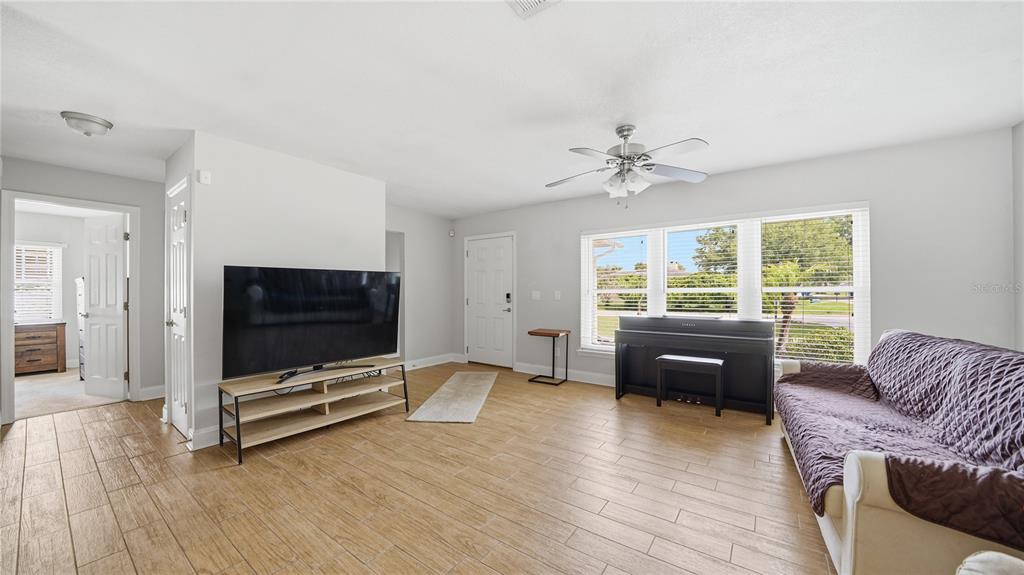 A living room with light-colored walls, wood-look tile floors, a television, and a piano — 125 BLUEFISH AVENUE, PONTE VEDRA BEACH, FL