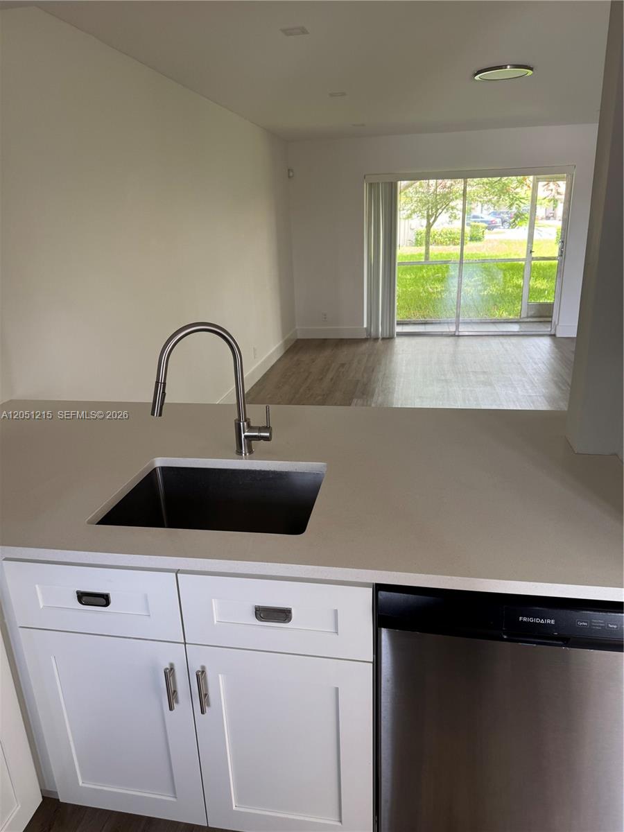 A kitchen sink and counter overlook a living area with a sliding glass door — 9937 Three Lakes Cir # 14d, Boca Raton FL 33428, BOCA RATON, FL