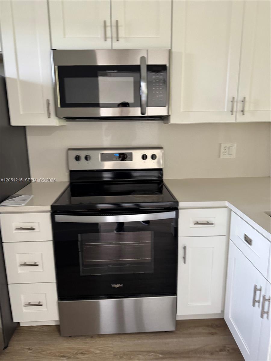 A kitchen features white cabinets, stainless steel appliances, and light-colored countertops — 9937 Three Lakes Cir # 14d, Boca Raton FL 33428, BOCA RATON, FL