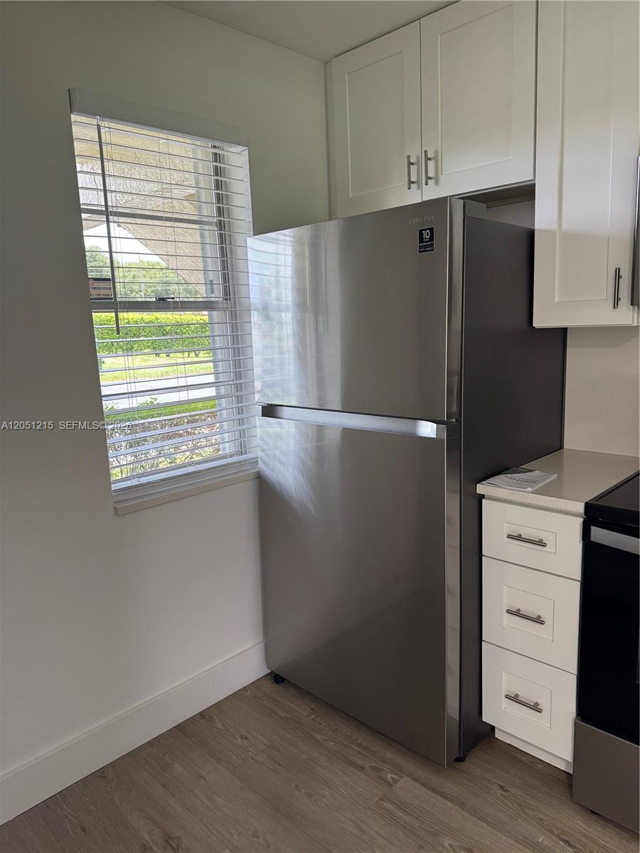 A stainless steel refrigerator stands next to white cabinets and a window with blinds — 9937 Three Lakes Cir # 14d, Boca Raton FL 33428, BOCA RATON, FL