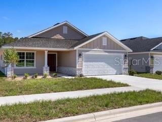 A single-story suburban house features a two-car garage, tan siding, and a stone-accented exterior — 16766 NW 178TH TERRACE, ALACHUA, FL