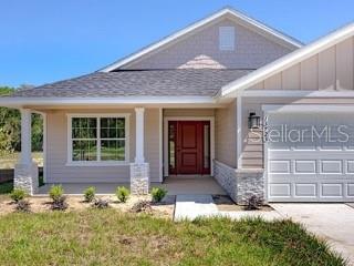 A single-story house with beige siding, a stone base, and a white garage door — 16766 NW 178TH TERRACE, ALACHUA, FL