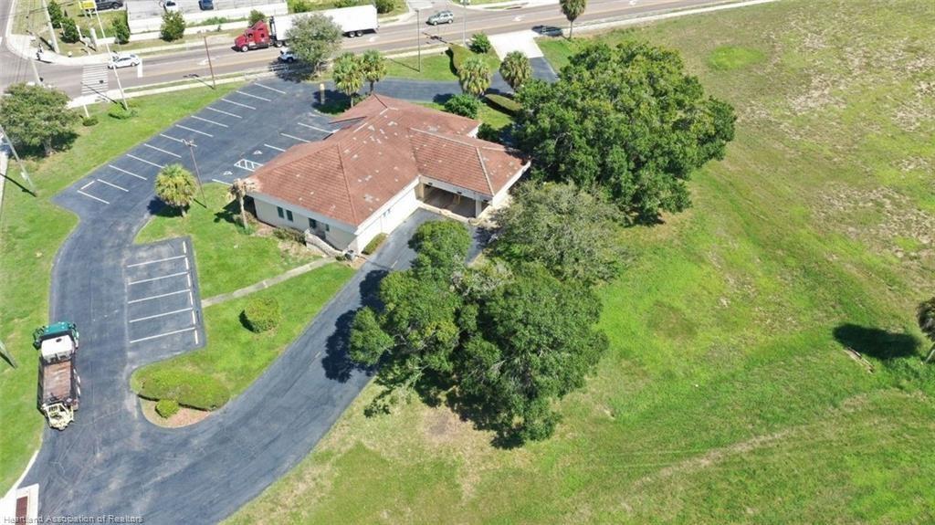 An aerial view shows a commercial building with a parking lot and surrounding green space — 695 N Scenic Highway, FL 33843, FL