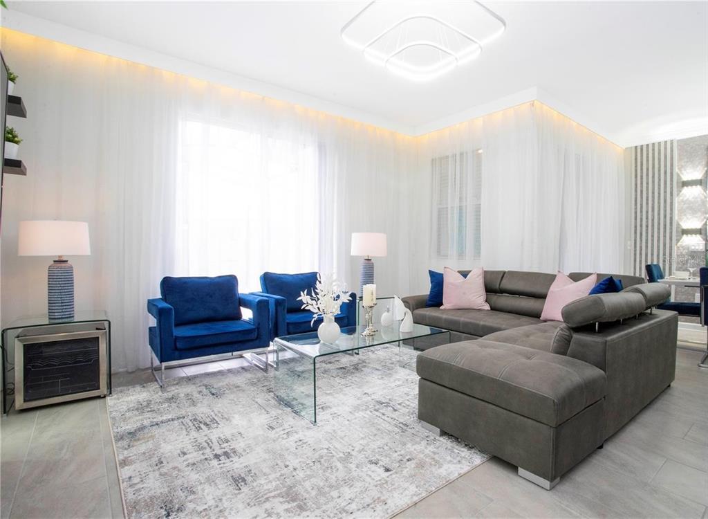 A living room features a grey sectional sofa, two blue velvet chairs, and a glass table — 4289 PARAGRAPH DRIVE, KISSIMMEE, FL