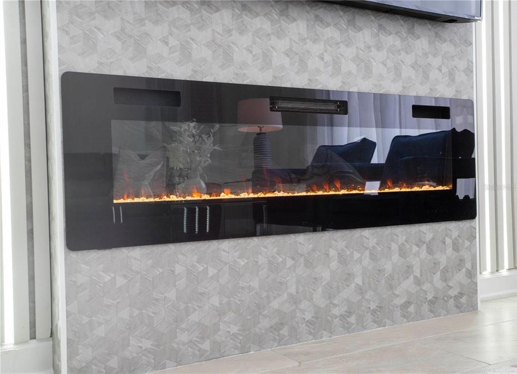 A wall-mounted electric fireplace with a black glass front is set against patterned wallpaper — 4289 PARAGRAPH DRIVE, KISSIMMEE, FL