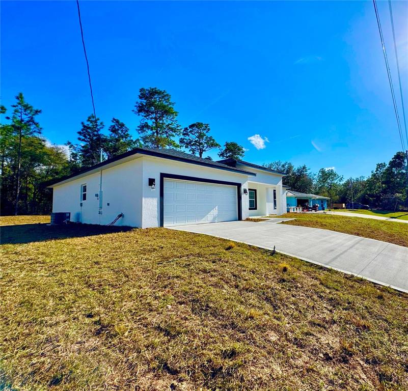 A white single-story house with a two-car garage and a concrete driveway — 10375 N CITRUS SPRINGS BOULEVARD, CITRUS SPRINGS, FL