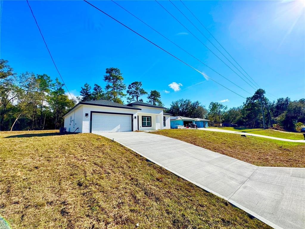 A white single-story house with a two-car garage and a concrete driveway — 10375 N CITRUS SPRINGS BOULEVARD, CITRUS SPRINGS, FL