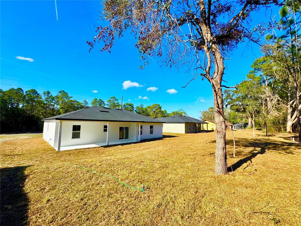 The exterior of a white, single-story house with a dark roof sits on a grassy lot — 10375 N CITRUS SPRINGS BOULEVARD, CITRUS SPRINGS, FL