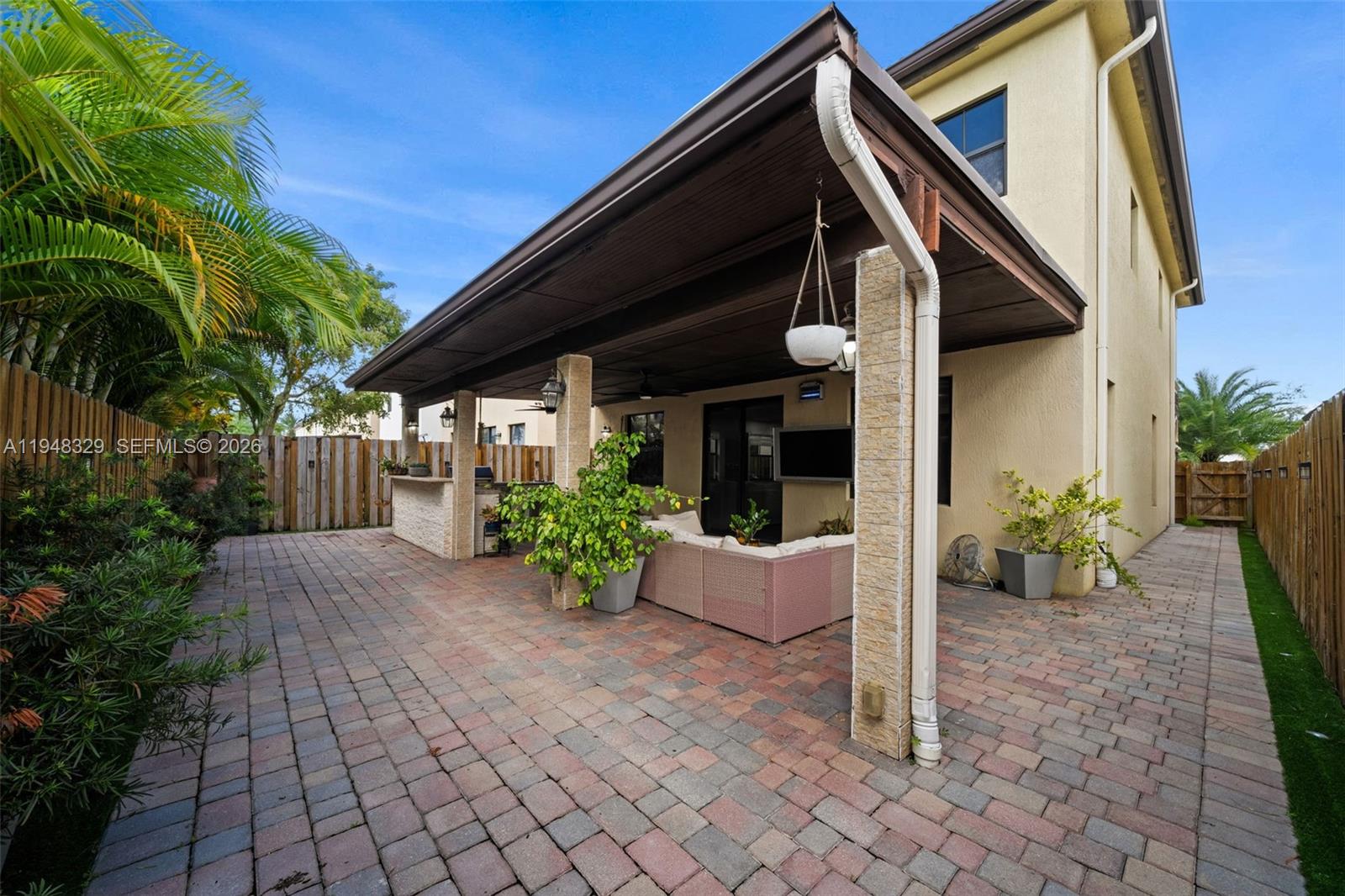 A paved patio features a covered outdoor living area with a bar and seating — 8658 NW 99th Path, Doral FL 33178, DORAL, FL