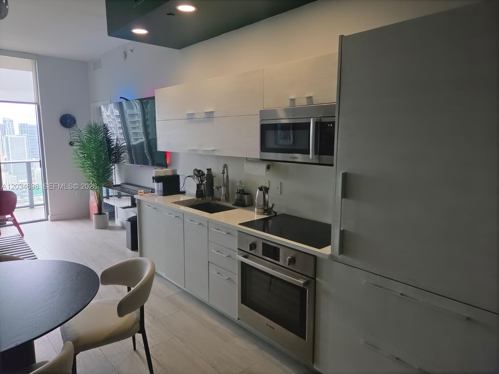 A modern kitchen features white cabinetry, stainless steel appliances, and a view of city buildings — 45 SW 9th St # 4309, Miami FL 33130, MIAMI, FL