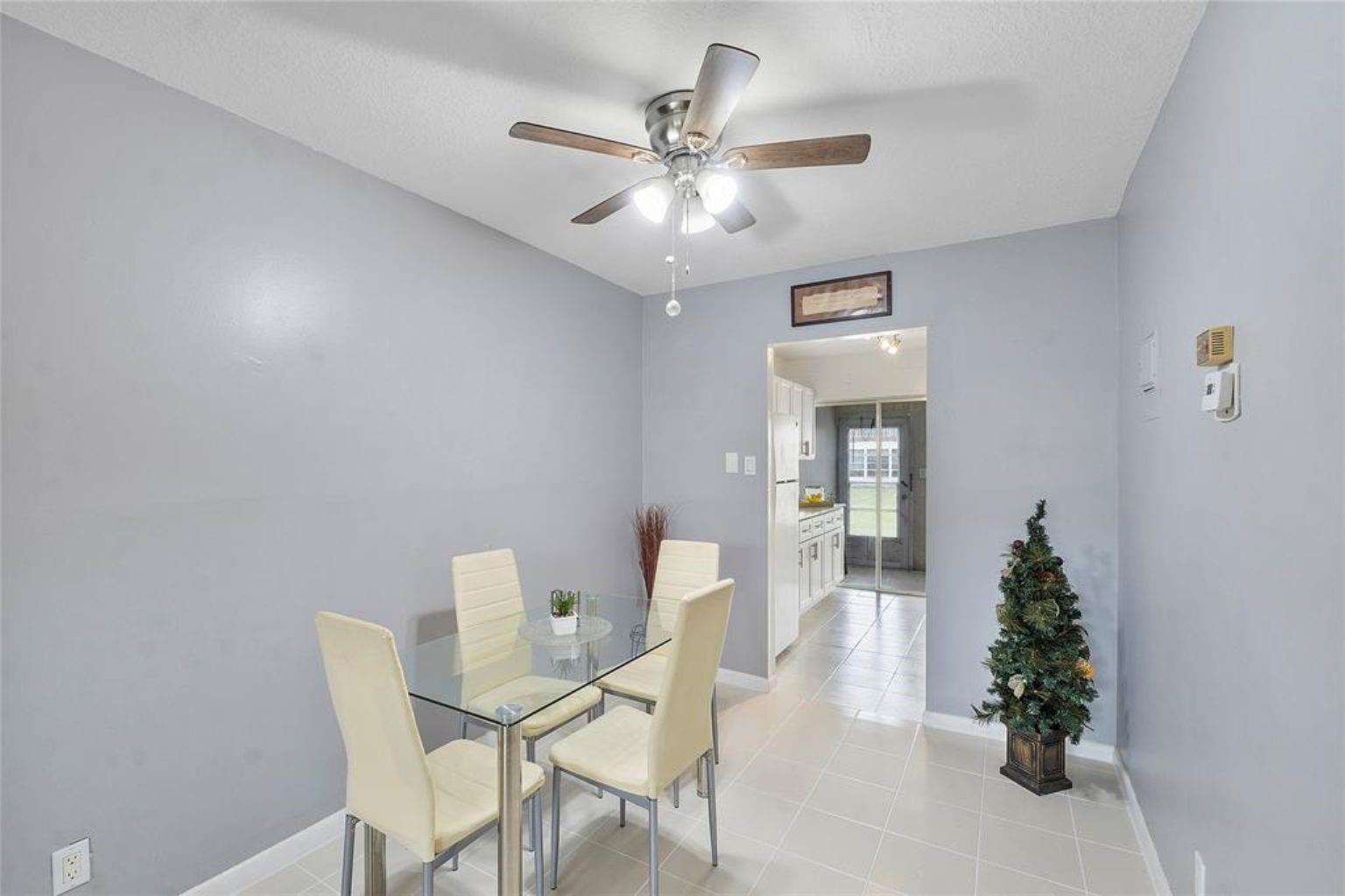 A dining area with light gray walls, tile flooring, a glass table, and a ceiling fan — 7500 NW 5th Court # 104, Margate FL 33063, MARGATE, FL