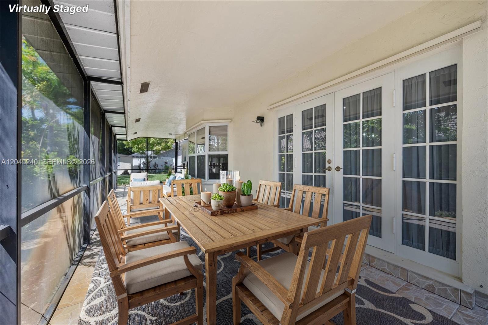 A covered patio features a wooden dining set on a patterned rug near glass doors — 4870 Hawkes Bluff Ave, Davie FL 33331, DAVIE, FL