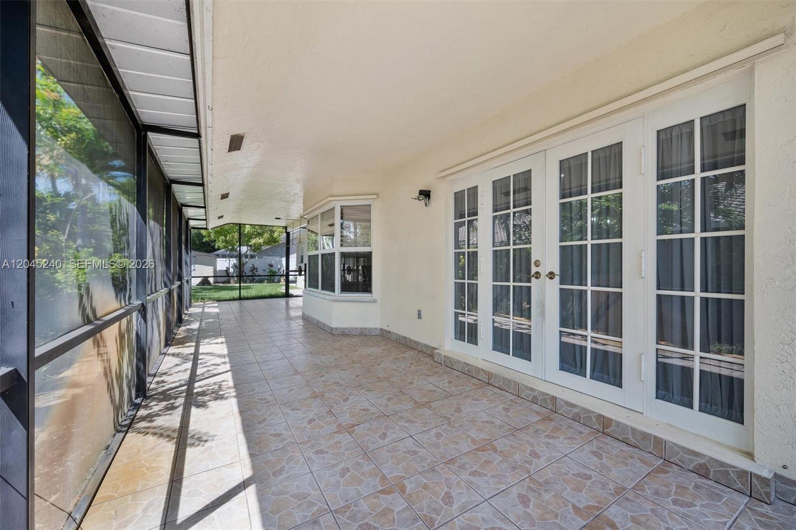 A covered patio features tiled flooring, a screened enclosure, and white French doors — 4870 Hawkes Bluff Ave, Davie FL 33331, DAVIE, FL