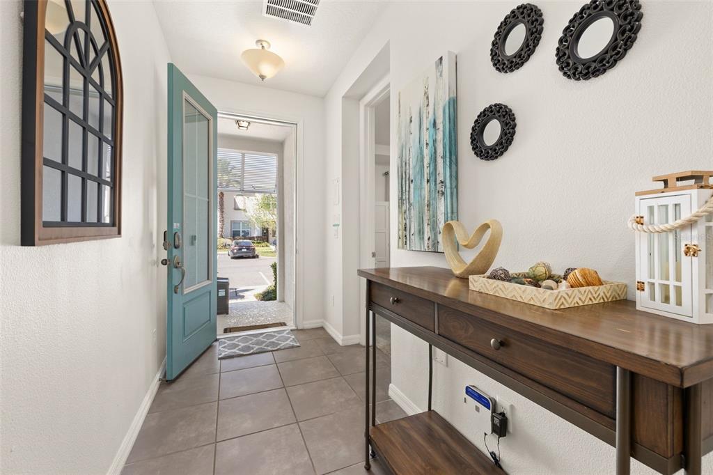 An entryway features a teal front door, tile flooring, and a wooden console table — 1539 CAREY PALM CIRCLE, KISSIMMEE, FL
