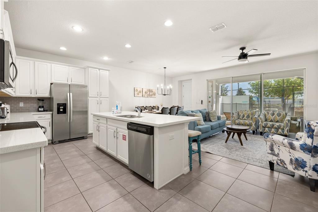 A kitchen with white cabinets and a center island opens into a living and dining area — 1539 CAREY PALM CIRCLE, KISSIMMEE, FL