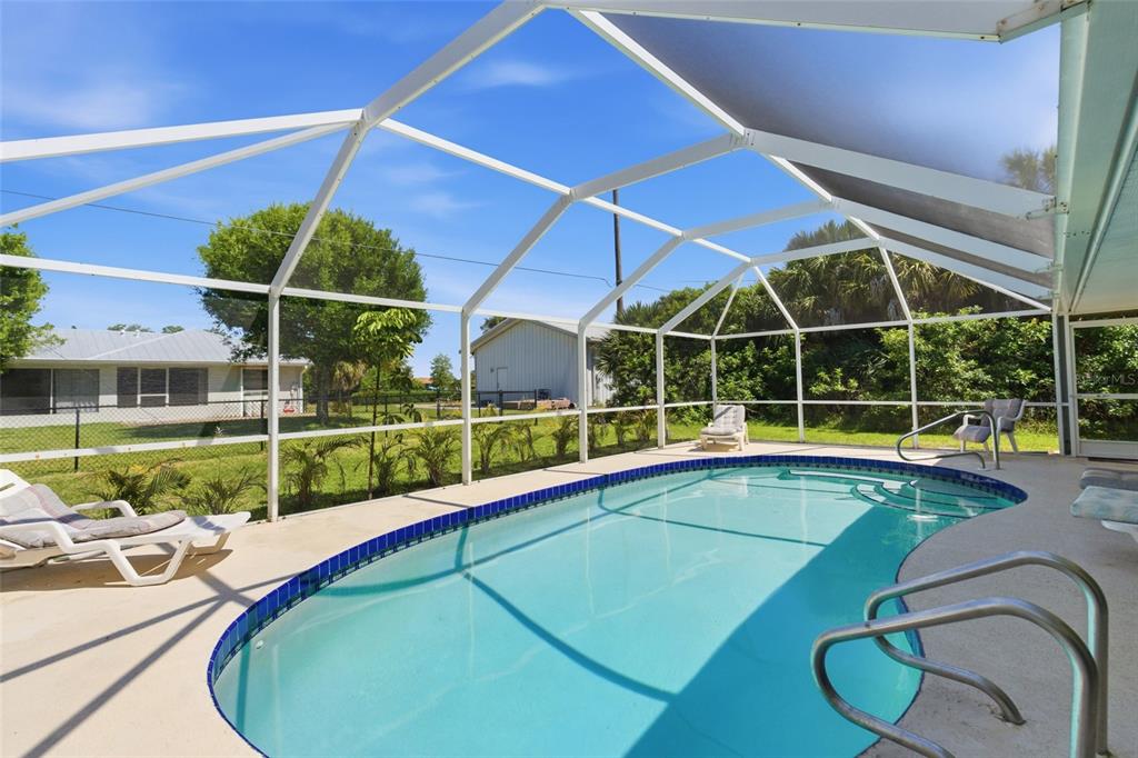 A screened-in swimming pool with a concrete deck sits in a backyard with landscaping — 4248 KILPATRICK STREET, PORT CHARLOTTE, FL