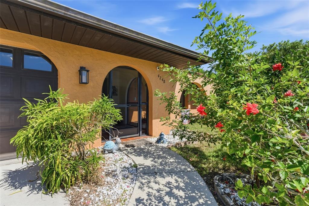 A walkway leads to the arched front entrance of a house with orange stucco walls — 4248 KILPATRICK STREET, PORT CHARLOTTE, FL