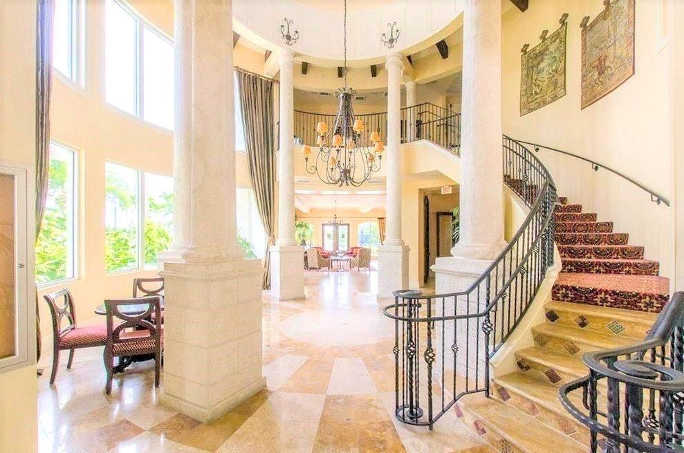 A grand foyer features a curved staircase, stone columns, a chandelier, and marble flooring — 4102 Tuscany Way # 4102, Boynton Beach FL 33435, BOYNTON BEACH, FL