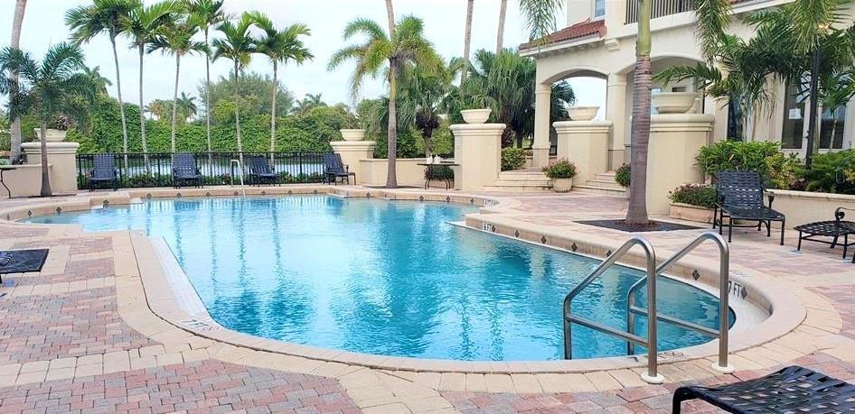 A swimming pool with a metal ladder sits on a brick patio near a building — 4102 Tuscany Way # 4102, Boynton Beach FL 33435, BOYNTON BEACH, FL