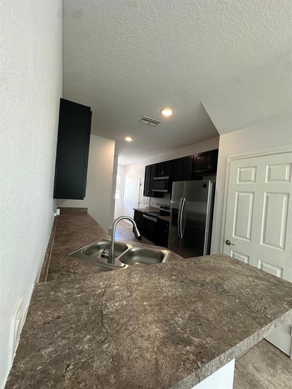 A kitchen features dark cabinets, stainless steel appliances, and a brown laminate countertop — 112 HOLLY VILLAGE DRIVE, DAVENPORT, FL