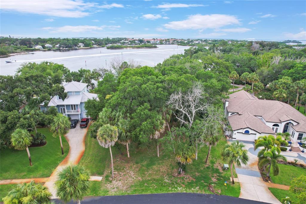 An aerial view shows a vacant lot situated between two houses near a waterfront — Lot 6 MEYERS COVE DRIVE, TARPON SPRINGS, FL
