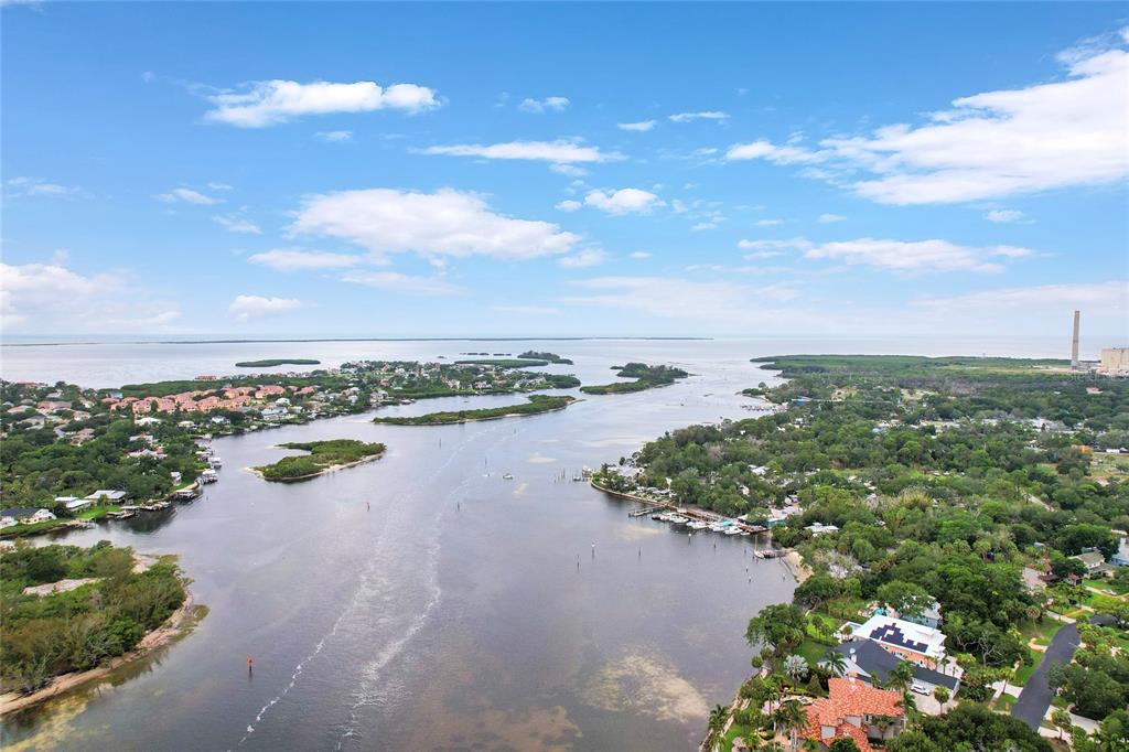 An aerial view shows a waterway winding through a coastal residential area with lush vegetation — Lot 6 MEYERS COVE DRIVE, TARPON SPRINGS, FL