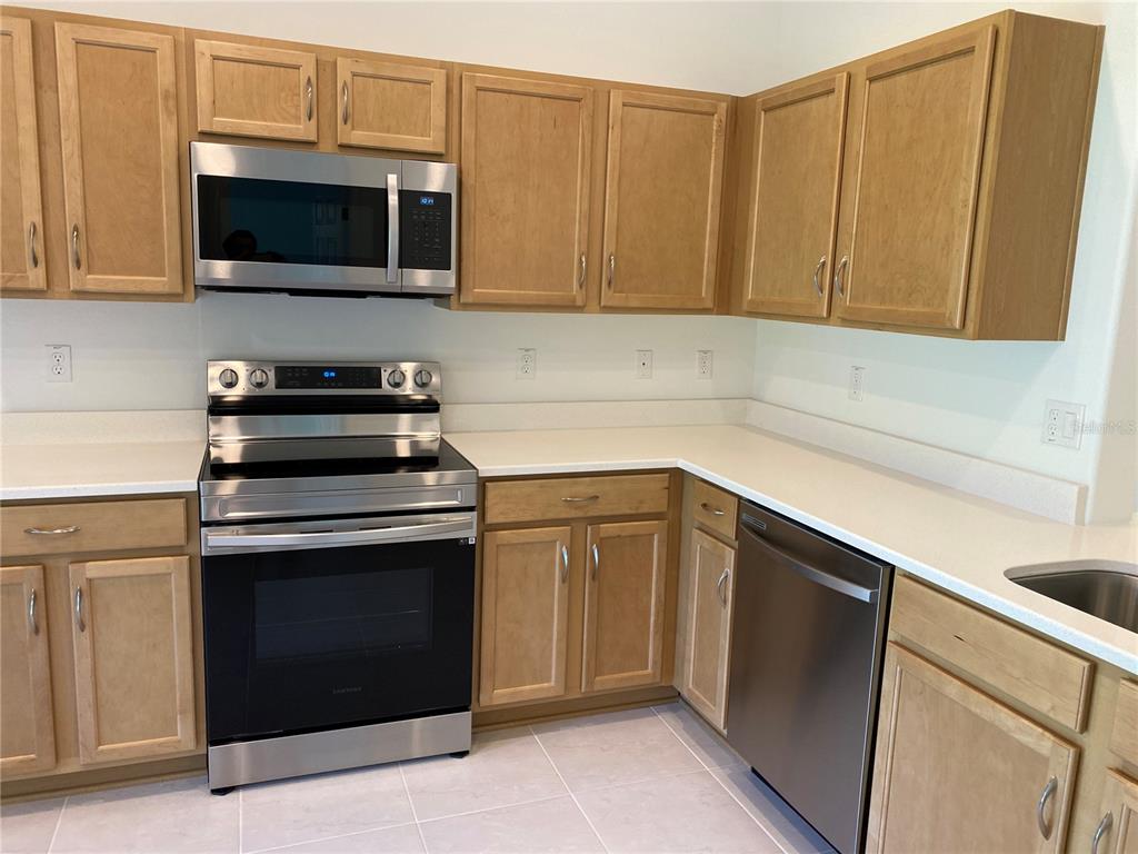 A kitchen features light wood cabinets, stainless steel appliances, and white countertops — 10 PONTIAC LANE UNIT B, PALM COAST, FL