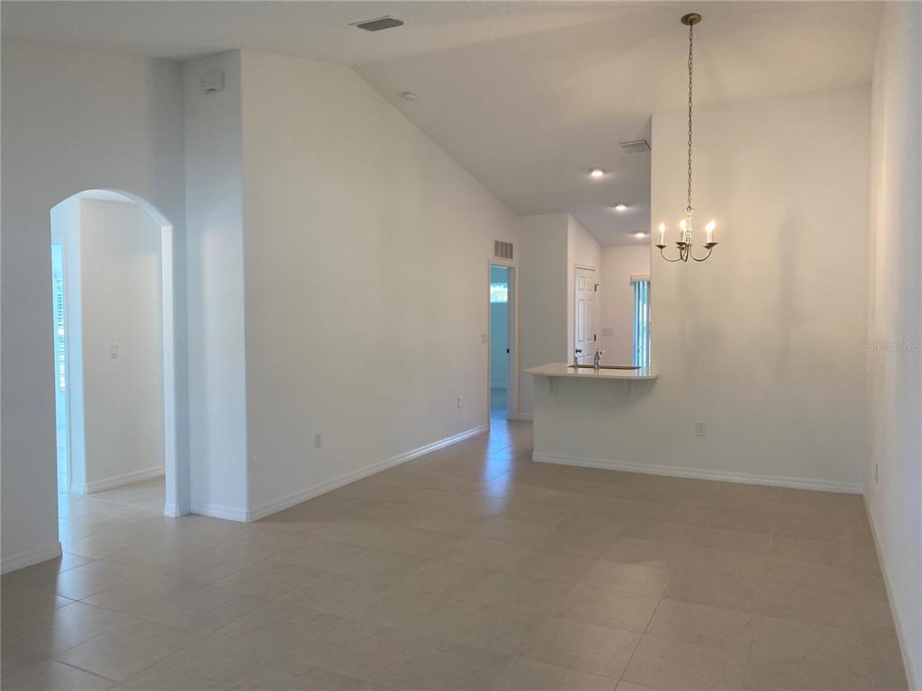 An open-concept living and dining area features light tile flooring, white walls, and a chandelier — 10 PONTIAC LANE UNIT B, PALM COAST, FL