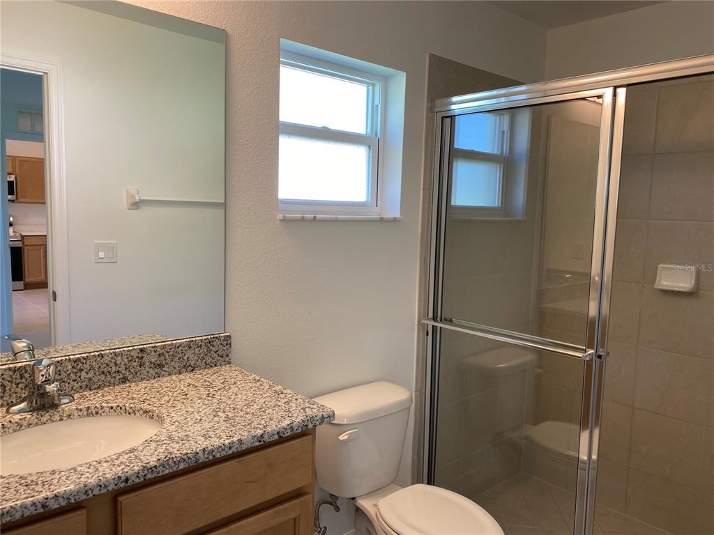 A bathroom features a granite vanity, a toilet, and a glass-enclosed shower — 10 PONTIAC LANE UNIT B, PALM COAST, FL