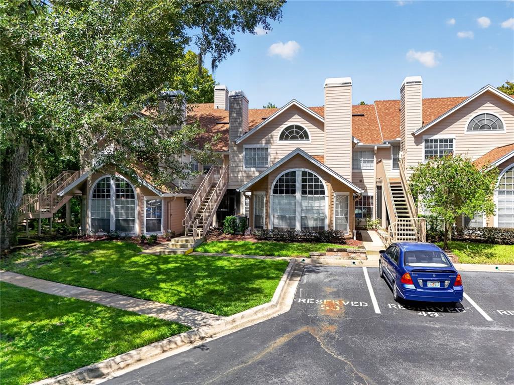 A multi-story apartment building with beige siding, arched windows, and exterior staircases near a parking lot — 610 COLORADO PLACE UNIT 50, ALTAMONTE SPRINGS, FL