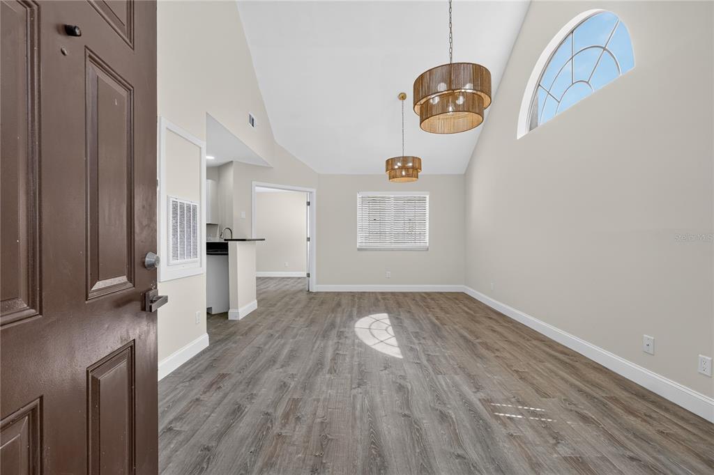 An open living area features vaulted ceilings, wood-look flooring, and two hanging drum pendant lights — 610 COLORADO PLACE UNIT 50, ALTAMONTE SPRINGS, FL
