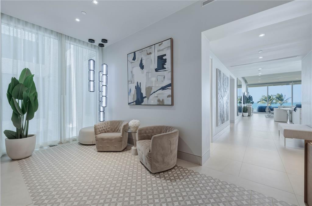 A modern foyer features two beige armchairs, a patterned rug, and a view toward the ocean — 7000 BAHIA BEACH BOULEVARD UNIT Ocean Drive 3301, RIO GRANDE, PR