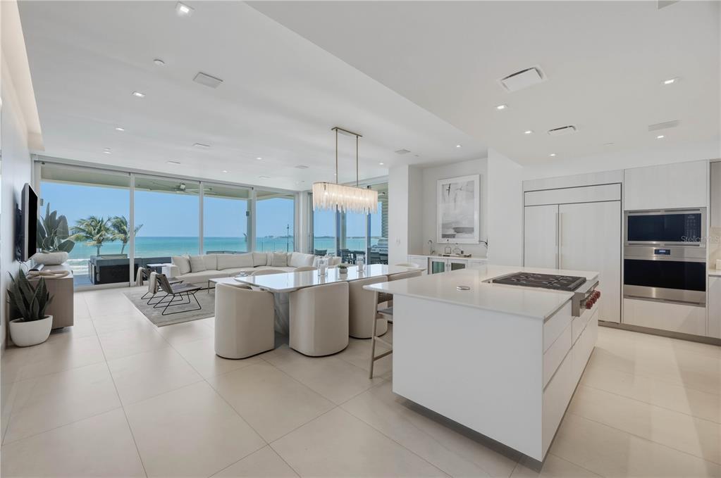 A modern open-concept kitchen and dining area features white cabinetry, a large island, and ocean views — 7000 BAHIA BEACH BOULEVARD UNIT Ocean Drive 3301, RIO GRANDE, PR