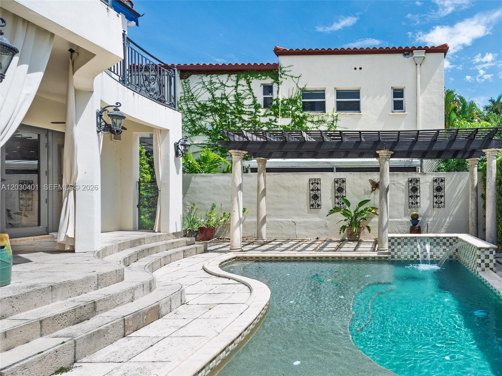 A backyard patio features a swimming pool, a pergola with stone columns, and curved steps — 5860 Pine Tree Dr, Miami Beach FL 33140, MIAMI BEACH, FL