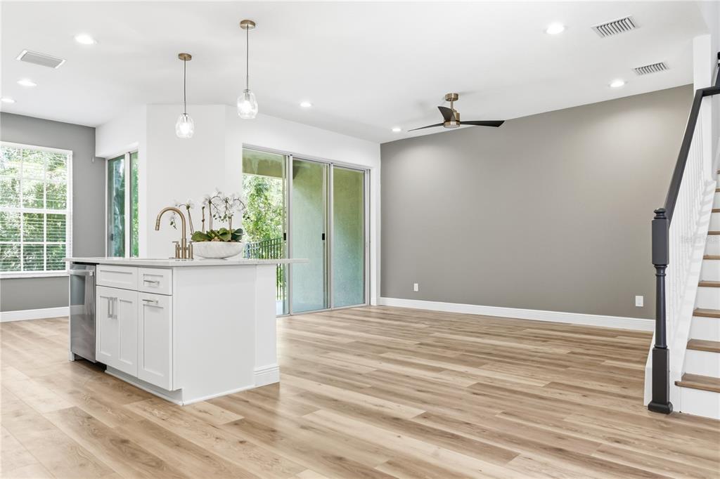 A bright open-concept kitchen and living area featuring light wood floors and a gray wall — 14409 MIRABELLE VISTA CIRCLE, TAMPA, FL