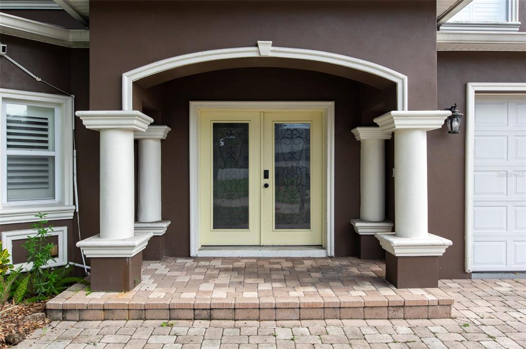 The exterior view shows a brown house entrance with white columns and double glass doors — 3814 W EL PRADO BOULEVARD, TAMPA, FL