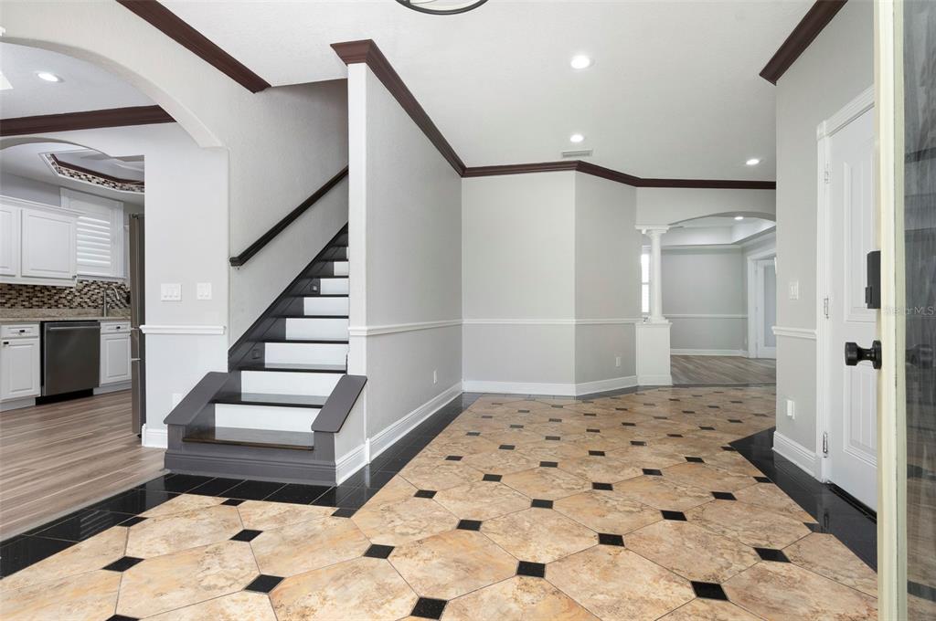 An entryway features a staircase with dark wood accents and patterned tile flooring — 3814 W EL PRADO BOULEVARD, TAMPA, FL