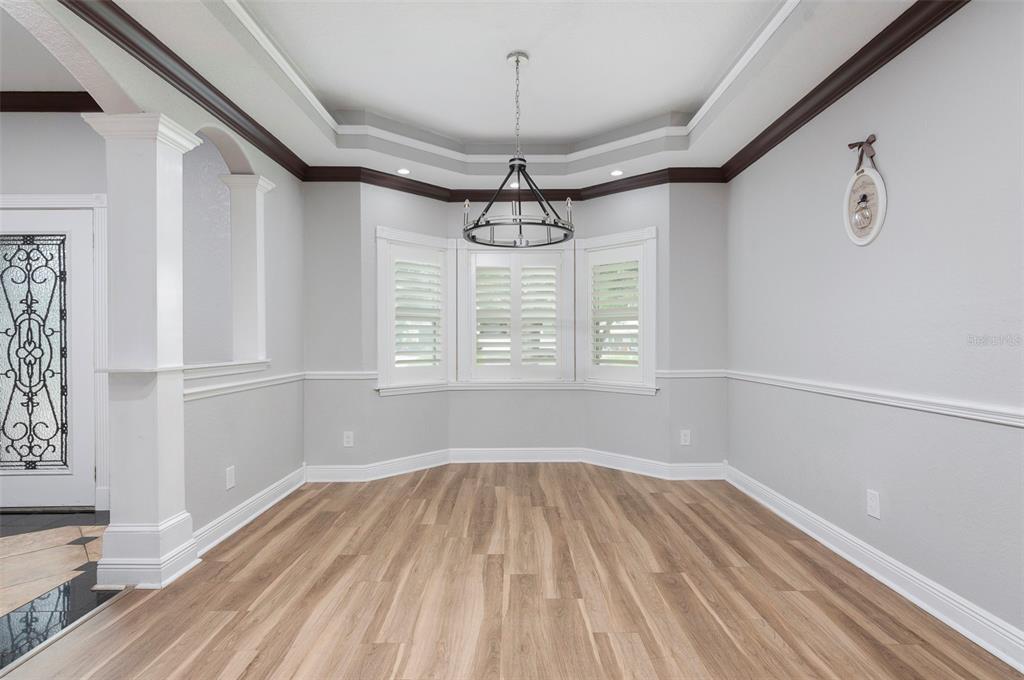 A dining room with light wood flooring, a tray ceiling, and a bay window — 3814 W EL PRADO BOULEVARD, TAMPA, FL