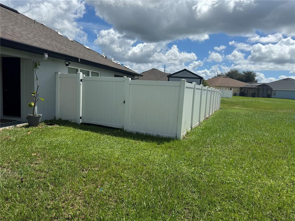 A white vinyl privacy fence encloses a backyard next to a house — 1191 SABINE LANE, KISSIMMEE, FL