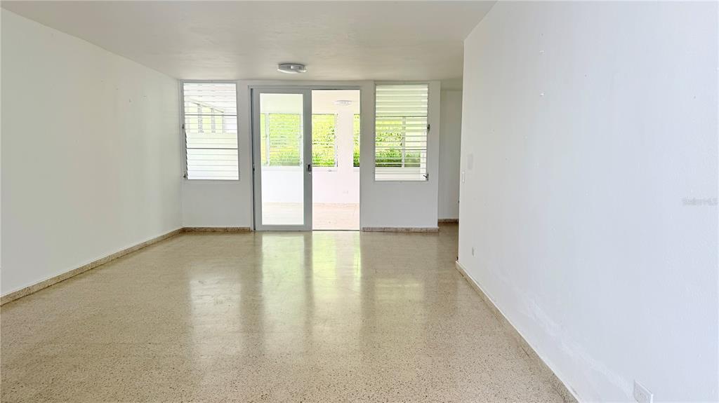 An empty room with white walls, terrazzo flooring, and a glass door leading to a balcony — 4-3 PASEO DE LA ALHAMBRA, GUAYNABO, PR