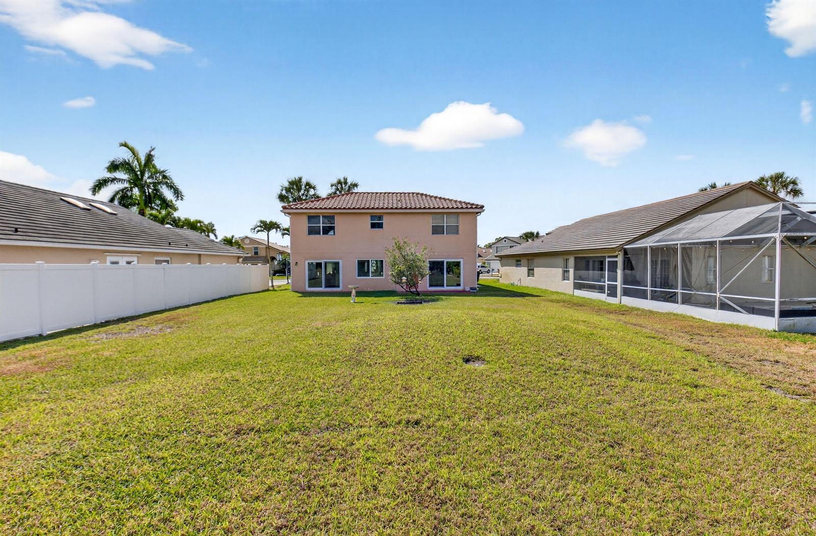 A two-story house with a large backyard sits between two neighboring homes under a blue sky — 6205 Balmy Court, Boynton Beach FL 33472, BOYNTON BEACH, FL