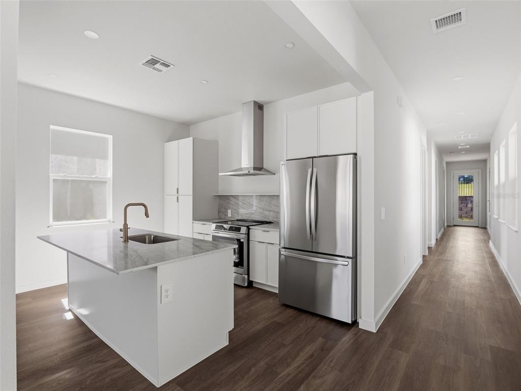 A modern kitchen features a marble-topped island, stainless steel appliances, and white cabinetry — 458 SKYFIELD COURT, LADY LAKE, FL