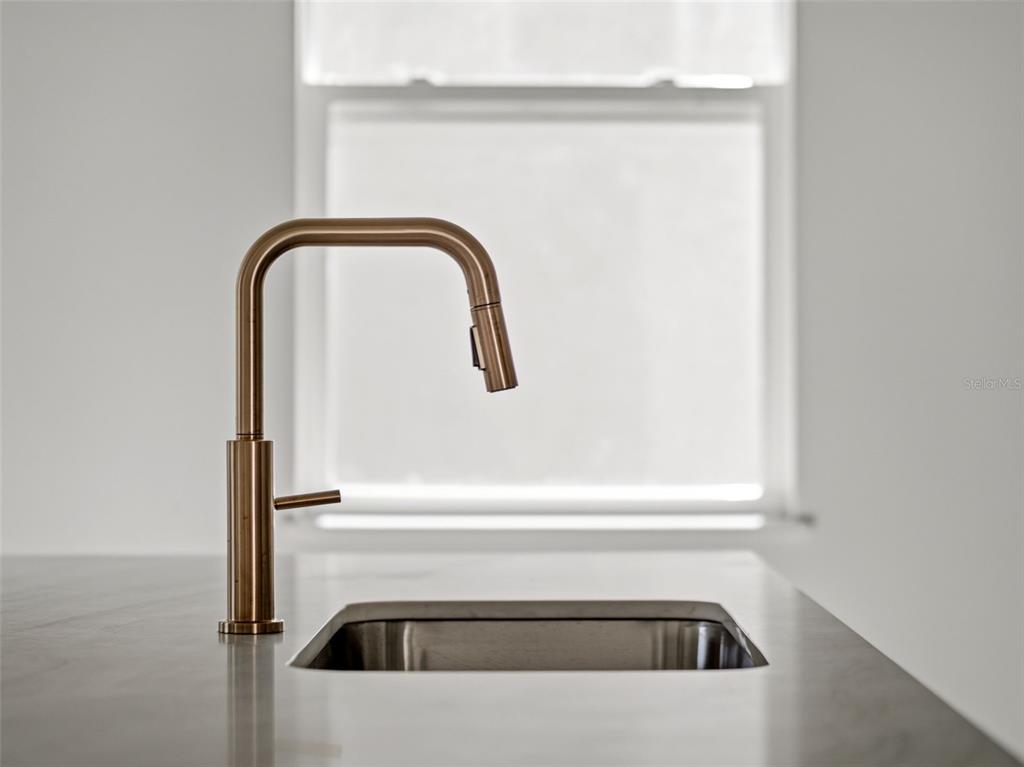 A modern bronze kitchen faucet stands next to a stainless steel sink on a countertop — 458 SKYFIELD COURT, LADY LAKE, FL