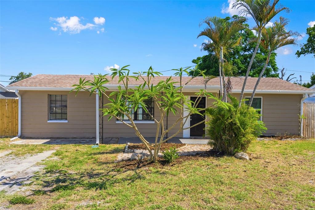 A single-story tan house with a brown shingled roof, a front yard, and palm trees — 4327 BEACON SQUARE DRIVE, HOLIDAY, FL