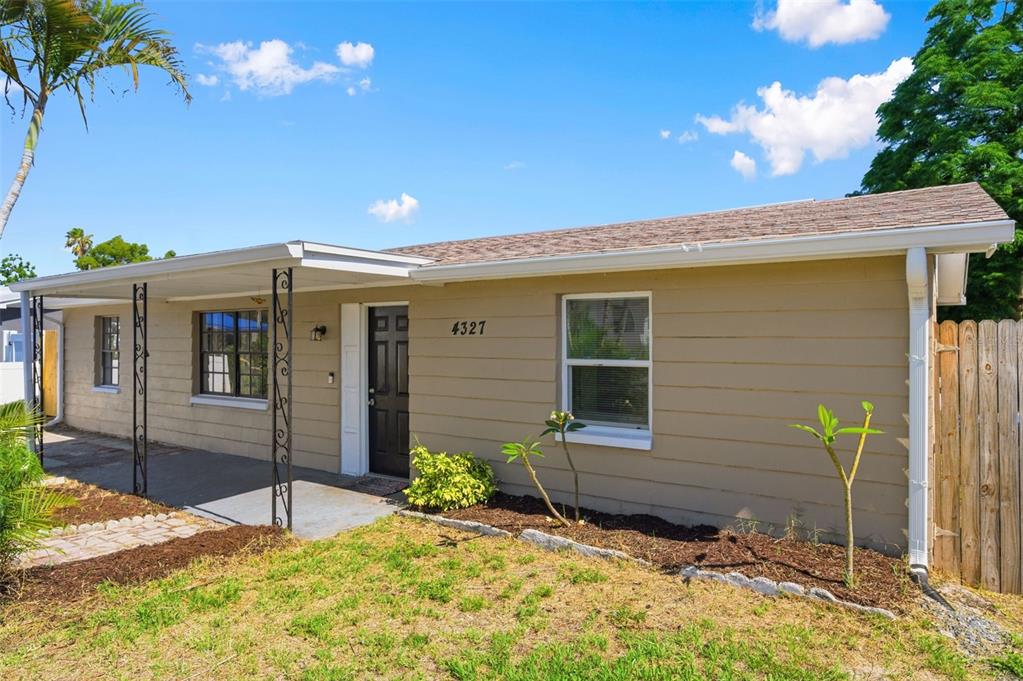 A single-story house with tan siding, a covered porch, and a black front door — 4327 BEACON SQUARE DRIVE, HOLIDAY, FL