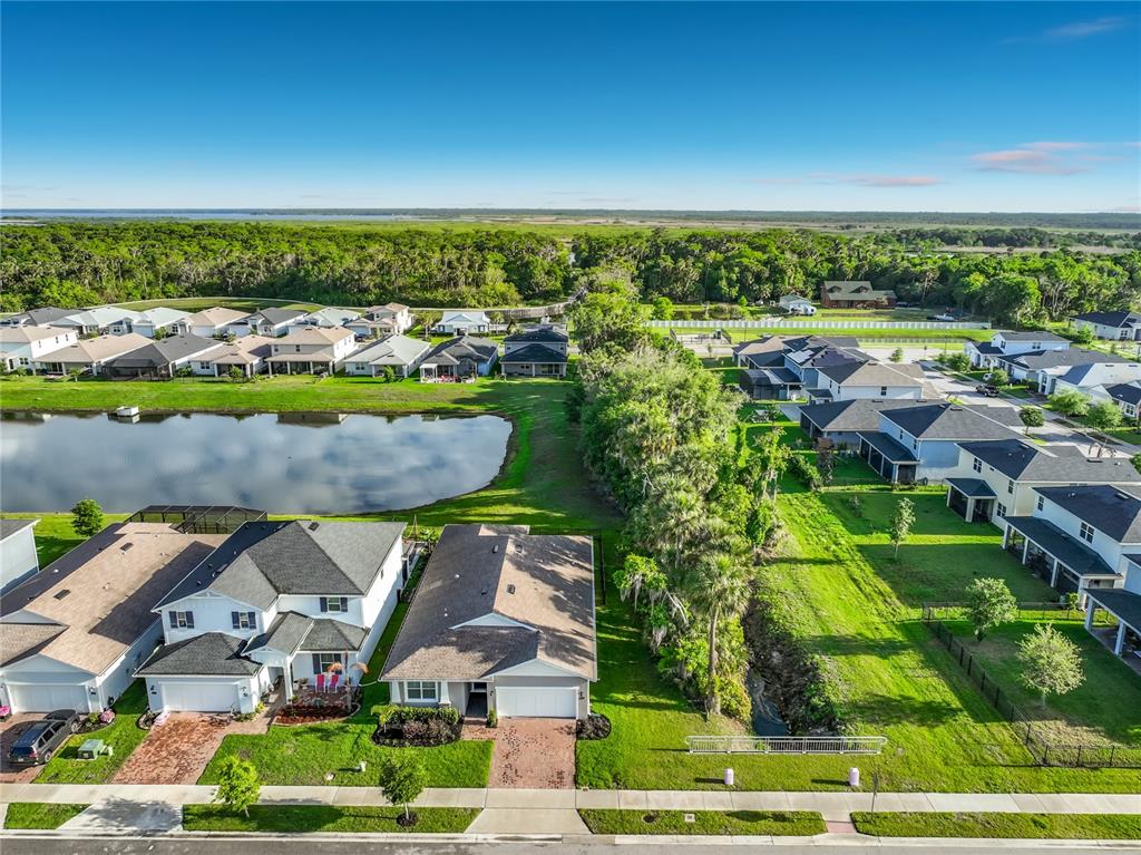 An aerial view shows a suburban neighborhood with houses, a pond, and a wooded area — 3412 BLUFF OAK LANE, SANFORD, FL