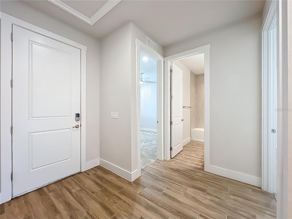 An interior hallway features wood-look tile flooring, white walls, and three white interior doors — 3412 BLUFF OAK LANE, SANFORD, FL